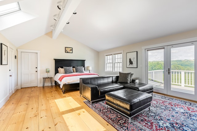 bedroom with french doors, lofted ceiling with skylight, access to exterior, track lighting, and light wood-type flooring