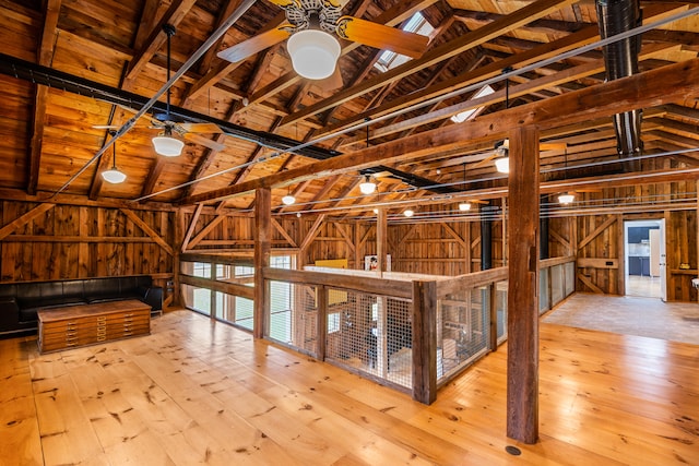 misc room featuring wooden walls, ceiling fan, and light wood-type flooring