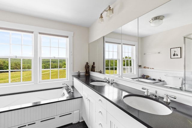 bathroom with a bath to relax in, baseboard heating, double sink, and oversized vanity