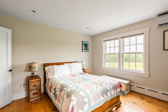 bedroom featuring an AC wall unit, baseboard heating, and light hardwood / wood-style floors