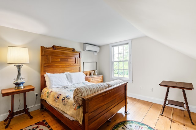 bedroom featuring lofted ceiling, light hardwood / wood-style flooring, and a wall mounted air conditioner