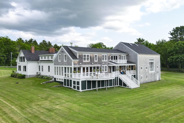 rear view of property with a deck, a sunroom, and a lawn