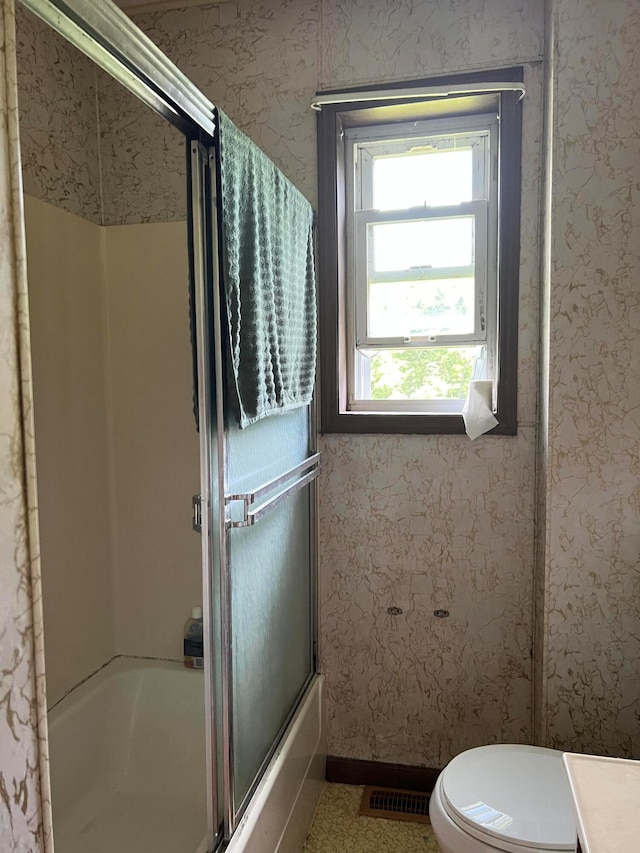 bathroom featuring toilet and enclosed tub / shower combo