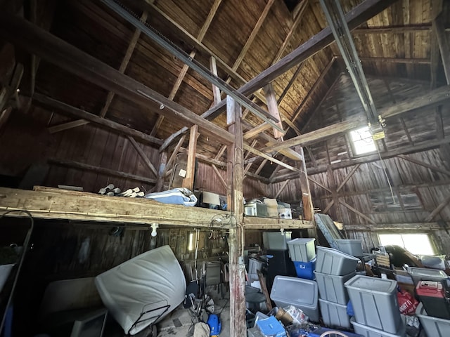 interior space featuring beam ceiling, high vaulted ceiling, and wood walls