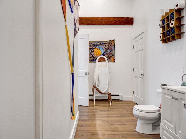 bathroom featuring toilet, wood-type flooring, a baseboard radiator, beamed ceiling, and vanity