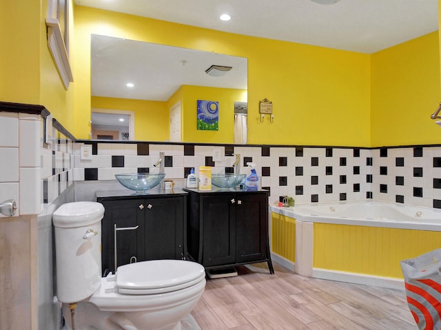 bathroom with toilet, a bathtub, wood-type flooring, and vanity