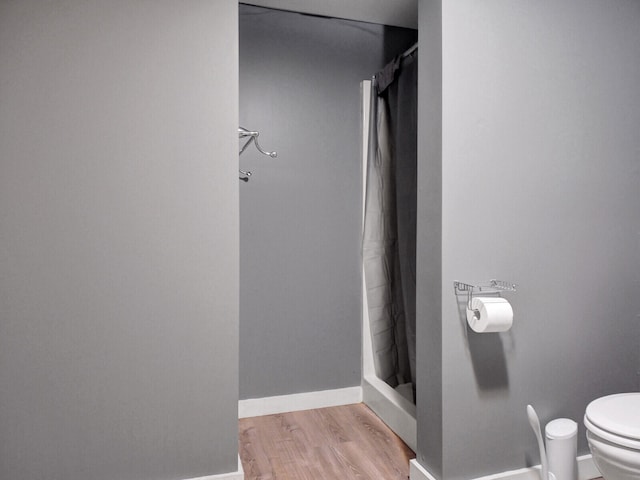 bathroom featuring toilet, walk in shower, and hardwood / wood-style floors