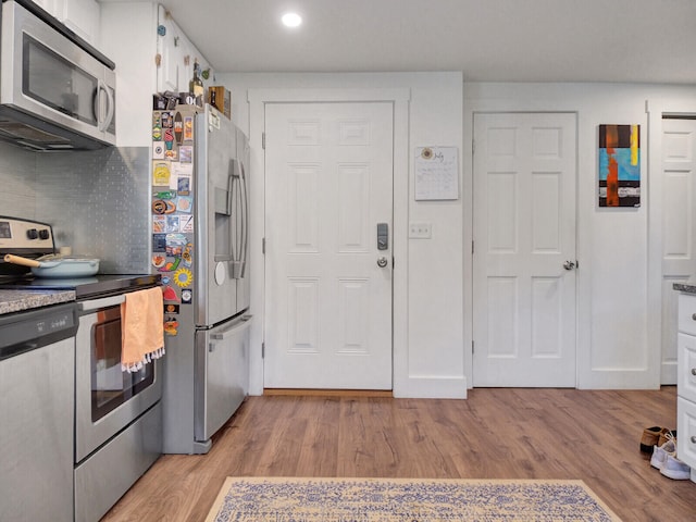 kitchen featuring light wood-type flooring, appliances with stainless steel finishes, backsplash, and white cabinetry