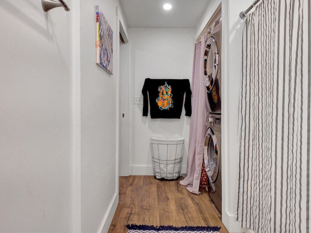 hallway with stacked washer and clothes dryer and wood-type flooring