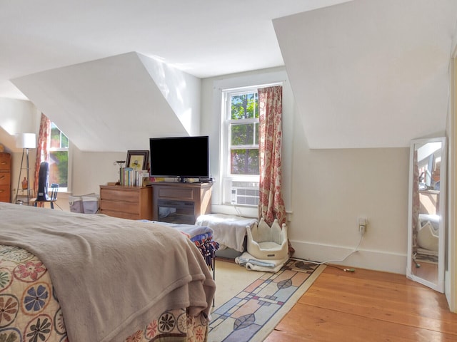 bedroom with lofted ceiling, cooling unit, and light wood-type flooring