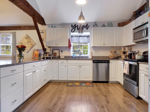 kitchen featuring stainless steel appliances, light wood-type flooring, vaulted ceiling with beams, pendant lighting, and white cabinetry