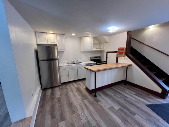 kitchen featuring sink, kitchen peninsula, appliances with stainless steel finishes, and white cabinetry