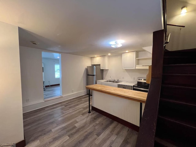 kitchen featuring appliances with stainless steel finishes, wood counters, a kitchen bar, white cabinets, and sink