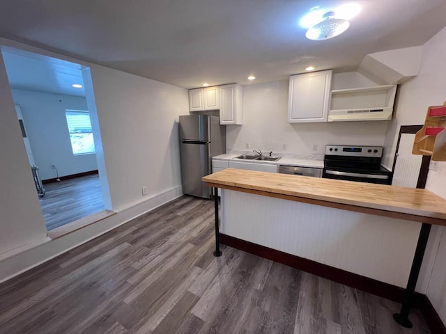 kitchen with sink, appliances with stainless steel finishes, white cabinets, wooden counters, and dark wood-type flooring