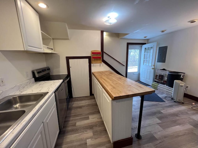 kitchen with electric range, electric panel, butcher block countertops, white cabinets, and sink