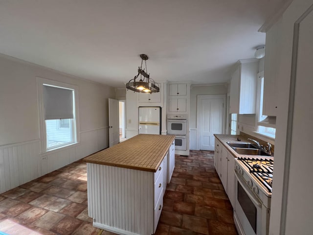 kitchen with sink, a kitchen island, white appliances, and white cabinetry