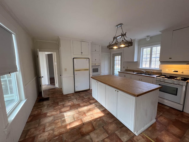 kitchen featuring decorative light fixtures, a center island, white cabinets, white appliances, and a chandelier