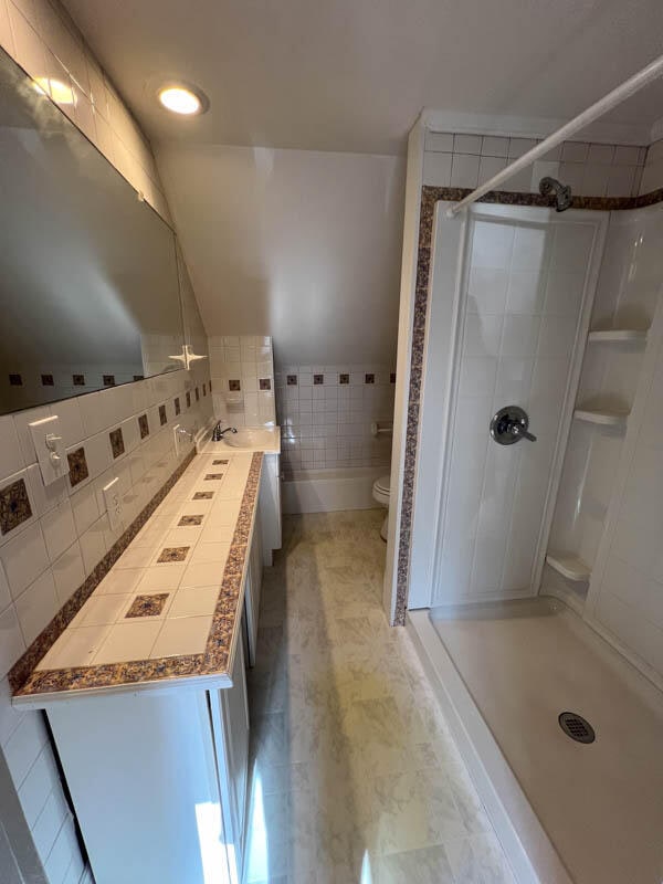 bathroom featuring shower with separate bathtub and toilet