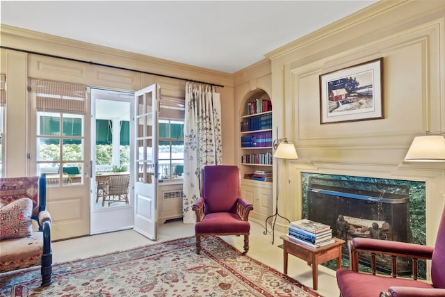 sitting room featuring light colored carpet, built in shelves, and a wealth of natural light