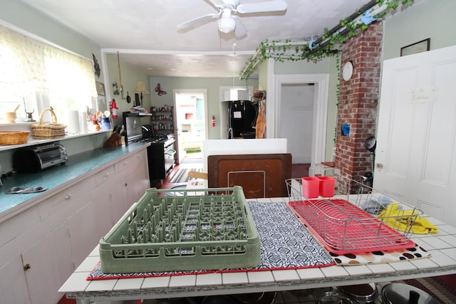 dining area featuring ceiling fan and brick wall