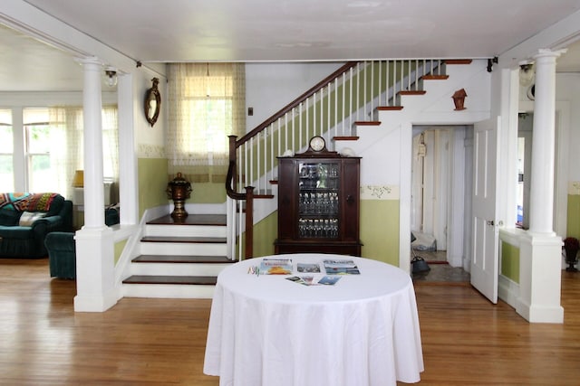 staircase featuring decorative columns, hardwood / wood-style floors, and a healthy amount of sunlight