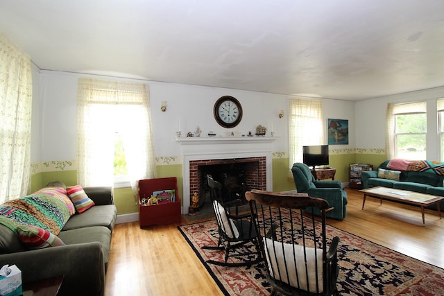 living room featuring a brick fireplace, plenty of natural light, and light wood-type flooring