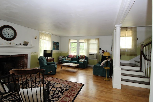 living room featuring light hardwood / wood-style flooring, decorative columns, and a brick fireplace