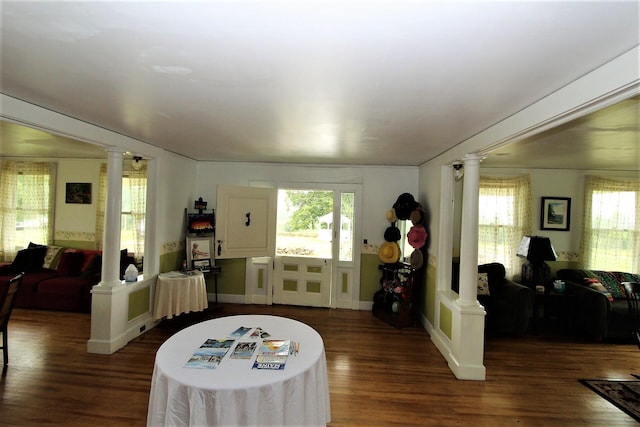 living room featuring decorative columns and dark wood-type flooring