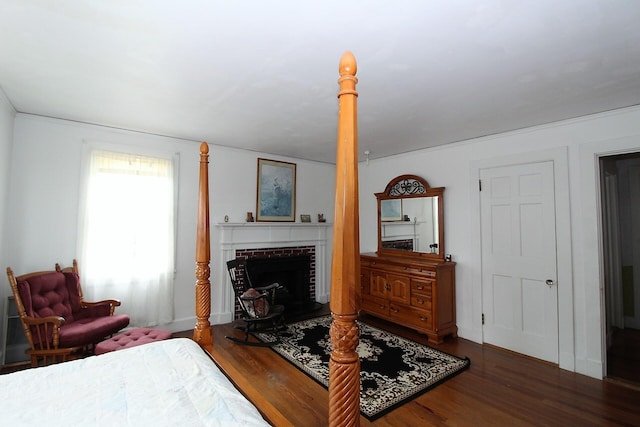 bedroom with a brick fireplace and dark hardwood / wood-style flooring