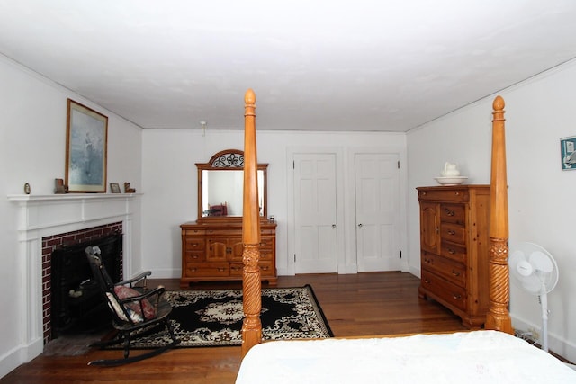 bedroom with crown molding, a fireplace, and dark wood-type flooring