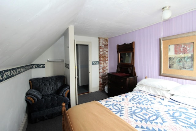 carpeted bedroom with lofted ceiling, a closet, and brick wall