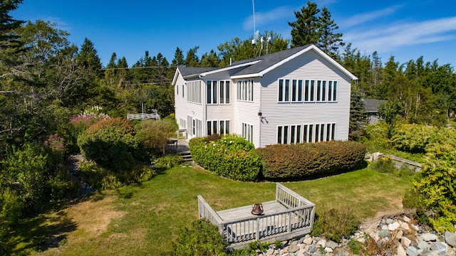 rear view of house featuring a deck and a lawn