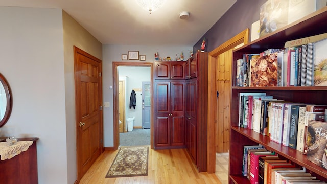 hallway featuring light wood-style flooring and baseboards