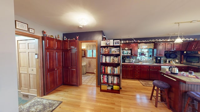 kitchen featuring light wood-type flooring, a kitchen bar, stainless steel appliances, and sink