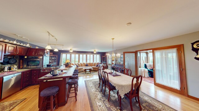 dining room featuring rail lighting, a notable chandelier, and light hardwood / wood-style flooring