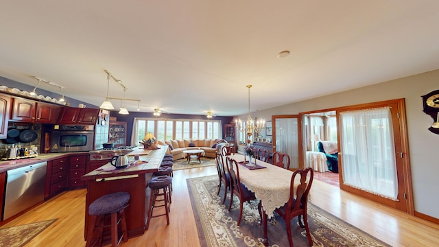 dining space featuring light wood-style floors, a notable chandelier, and rail lighting