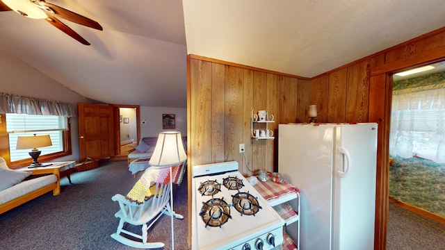 kitchen featuring vaulted ceiling, white appliances, carpet, ceiling fan, and wooden walls