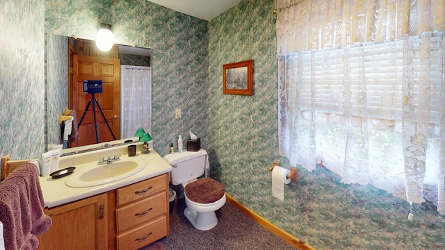 bathroom featuring baseboards, vanity, toilet, and wallpapered walls