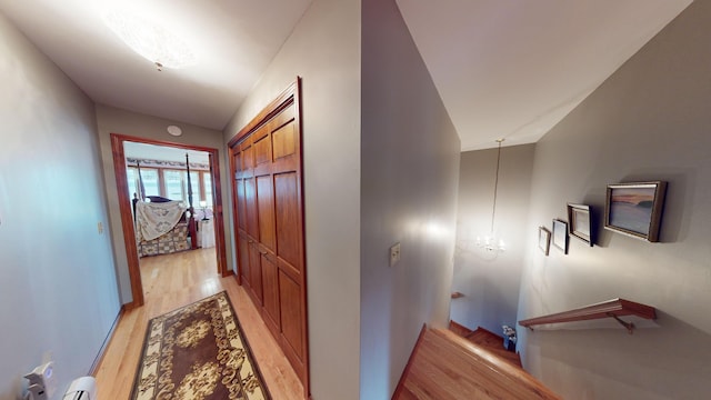 hallway with light wood-type flooring and a notable chandelier