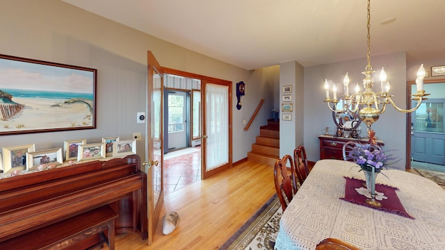 dining room featuring light wood finished floors, stairway, and an inviting chandelier