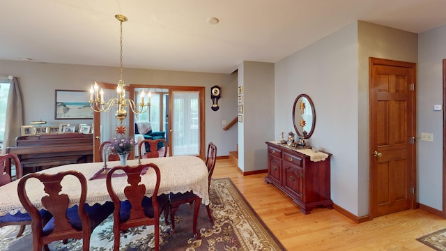 dining space with light wood-type flooring and an inviting chandelier