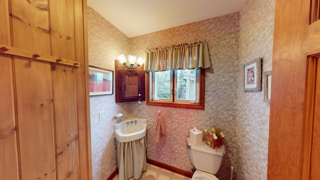 half bath with toilet, wallpapered walls, and baseboards