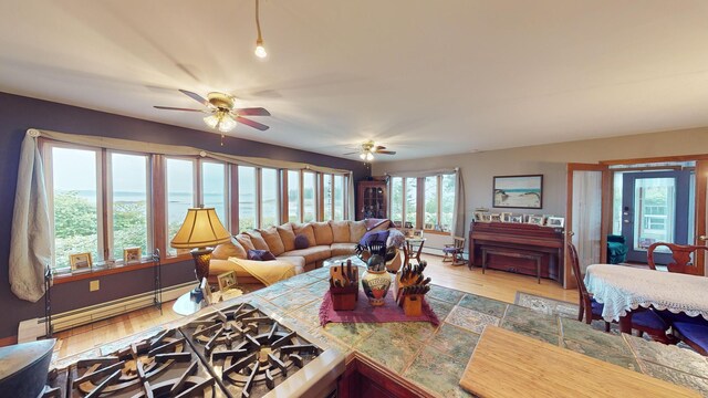 living room with a baseboard heating unit, a water view, ceiling fan, and light hardwood / wood-style floors