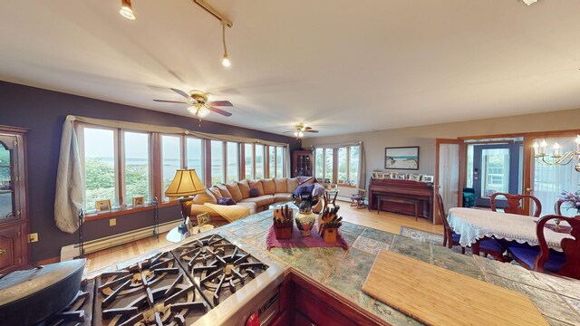 living room with light hardwood / wood-style flooring, ceiling fan with notable chandelier, a baseboard radiator, and track lighting