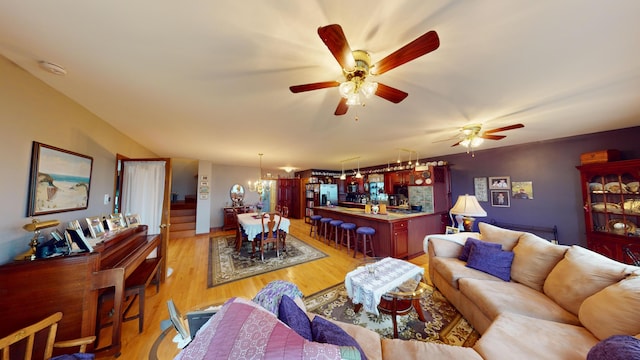 living room featuring ceiling fan with notable chandelier and light hardwood / wood-style floors