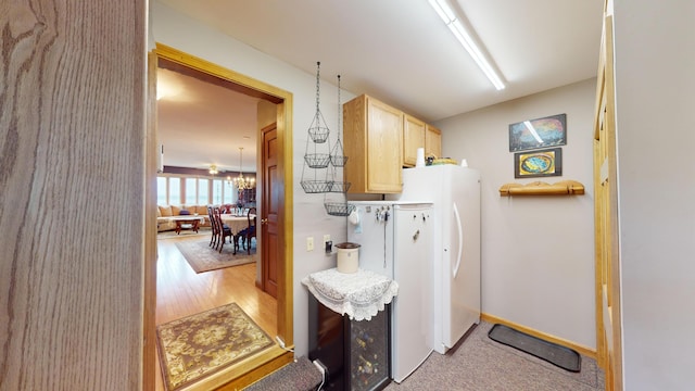 washroom with light wood-type flooring, washing machine and dryer, and a notable chandelier