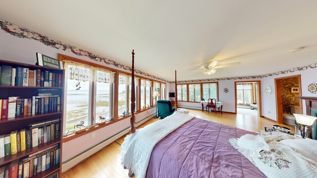 bedroom with a baseboard heating unit, light hardwood / wood-style flooring, and ceiling fan