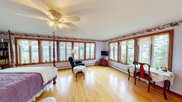 bedroom with baseboard heating, ceiling fan, and light hardwood / wood-style floors