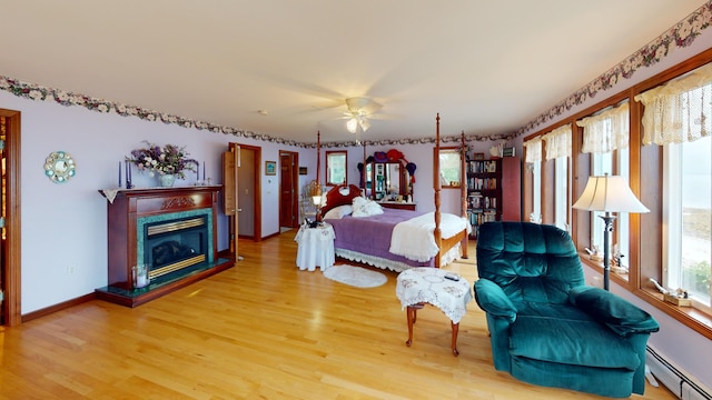 bedroom featuring hardwood / wood-style flooring, baseboard heating, and ceiling fan