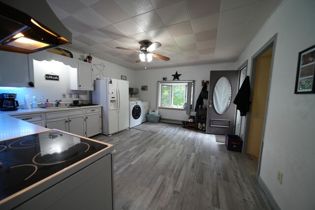 kitchen featuring ceiling fan, white fridge with ice dispenser, washer / dryer, white cabinets, and stove